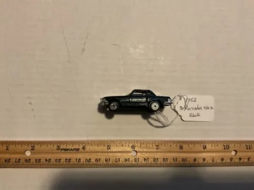 Black diecast model car with attached paper label, small scale vehicle