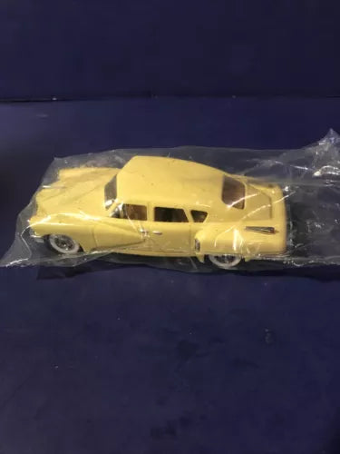 Yellow diecast model car in clear box, classic Tucker Torpedo shape