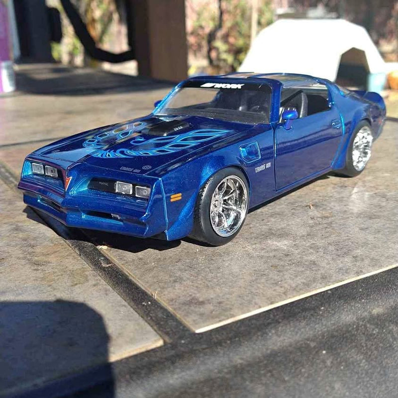 Blue 1/24 diecast car model with black hood and chrome wheels, front 3/4 view