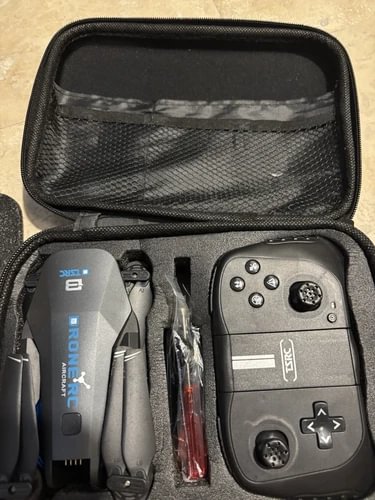 Drone with built-in Bluetooth camera in open black carrying case, with controller