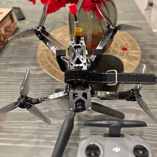 Black and gray drone with four propellers and front camera module.