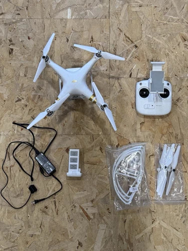 White quadcopter drone with remote controller, cables, and spare propellers