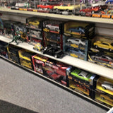 Diecast car assortment in boxed display on shelf, multiple yellow and dark cars