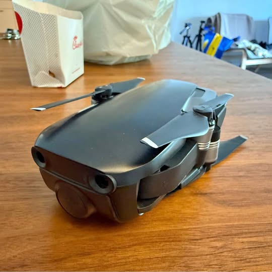 DJI drone with front camera lenses and foldable propeller arms, gray body
