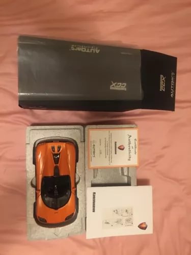 Orange diecast sports car model in box with instruction papers and foam insert