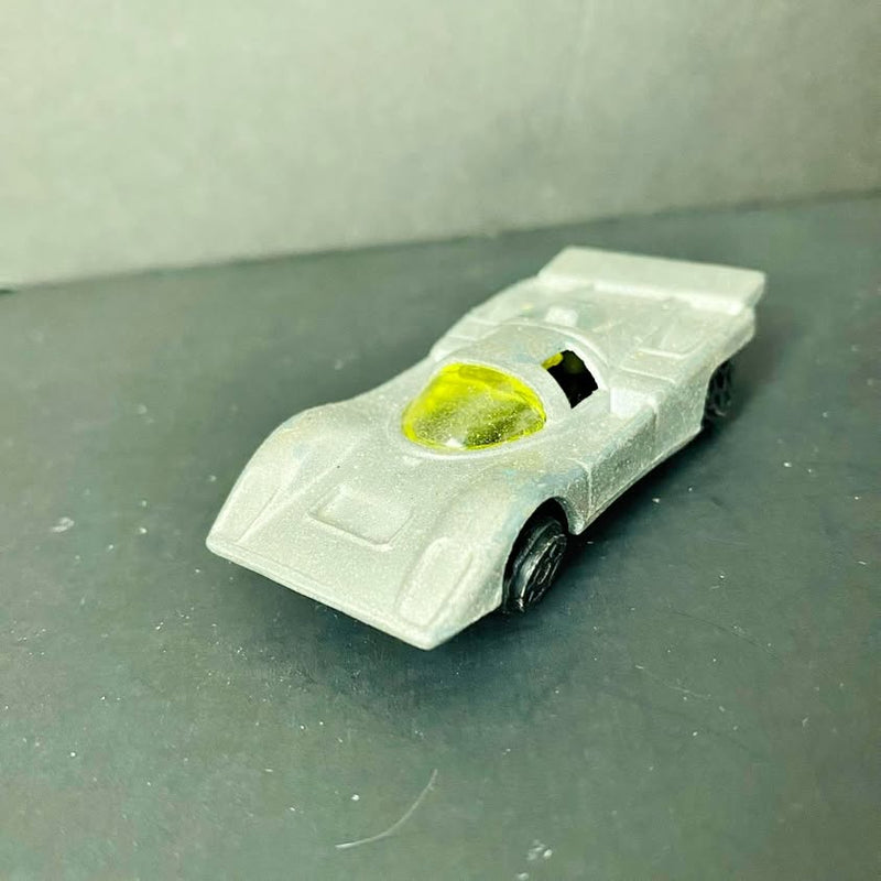 Vintage diecast toy car with silver body and green windshield, front three-quarter view