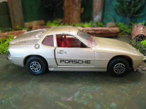 Gold diecast model car with PORSCHE logo, red interior, side view, 1/36 scale.