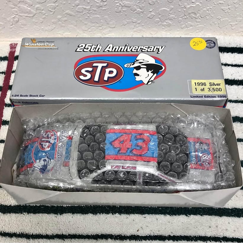 1:24 diecast race car in retail box, blue and red STP-style graphics