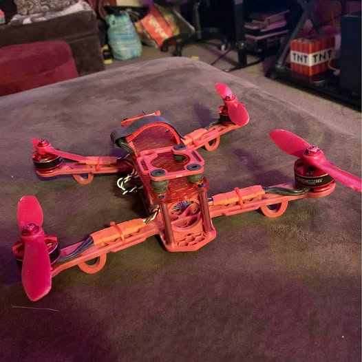 Racing drone with four pink propellers and red-orange frame