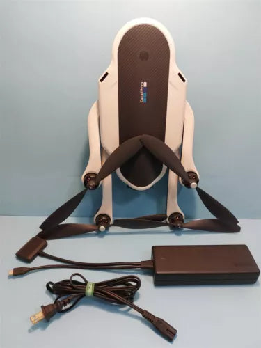 Folded quadcopter drone with attached propellers, battery pack and charging cables