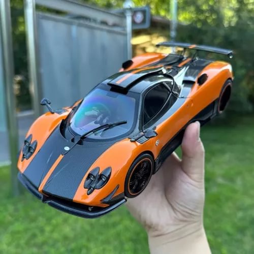 Orange and black diecast coupe model car with front hood detail, held in hand