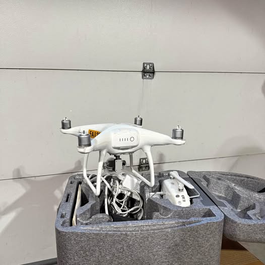 Broken white quadcopter drone with exposed internal wiring in gray foam tray