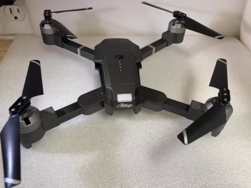 Attop quadcopter drone with four arms and propellers, black body and landing legs