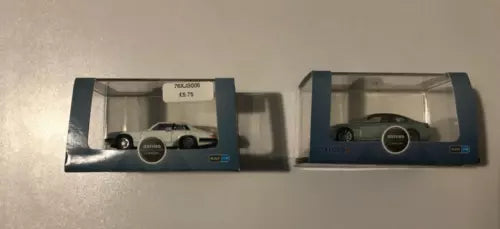 Diecast model cars in packaging, one white and one dark green, 1:76 scale