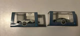 Diecast model cars in packaging, one white and one dark green, 1:76 scale