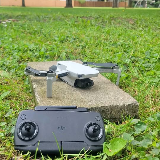 Gray foldable quadcopter drone with camera and remote controller on stone block