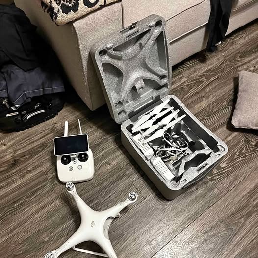 White DJI Phantom drone with controller and open hard case, showing internal parts