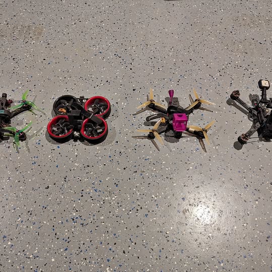 FPV drone set of four with red prop rings, pink center, and black frame