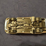 Diecast model car in metallic gold, underside view with detailed chassis and wheels