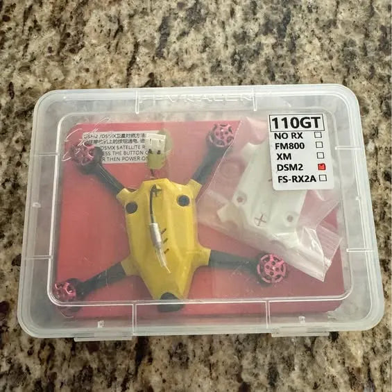 FPV drone parts in clear plastic box, yellow frame and wiring