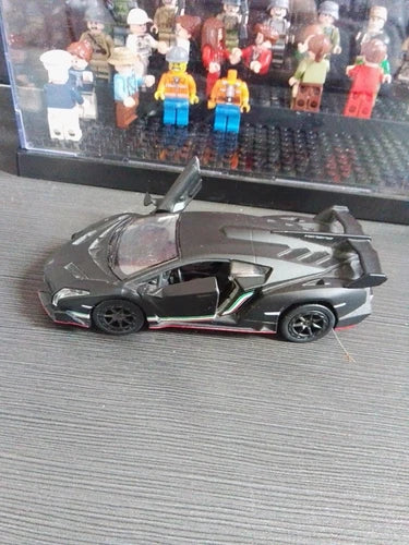 Diecast sports toy car with dark gray body, black details, and green stripe accents