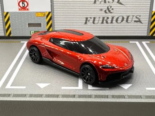 Red diecast sports car model with black wheels and tinted windows