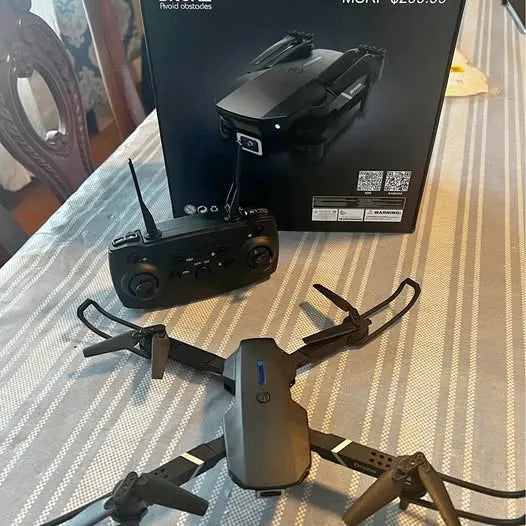 Black quadcopter drone with attached controller, four propellers visible