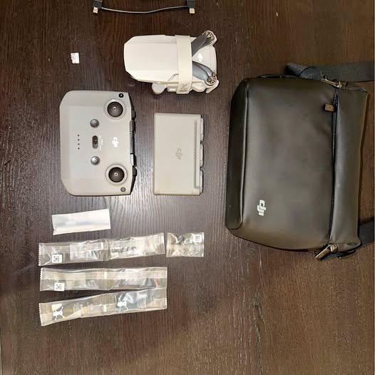 White drone with controller and carry case, plus included accessory bags