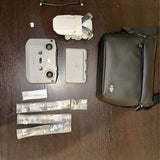 White drone with controller and carry case, plus included accessory bags