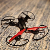 Red and black quadcopter drone with four propellers and protective guards