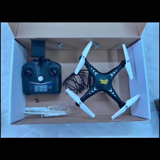 Quadcopter drone with blue propellers and black controller in open box