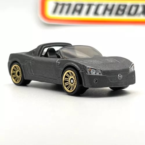 Dark grey metalflake diecast sports car with gold wheels and clear windshield