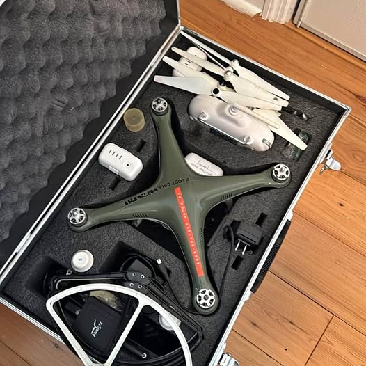 Folding quadcopter drone with gray body and green arms in protective case