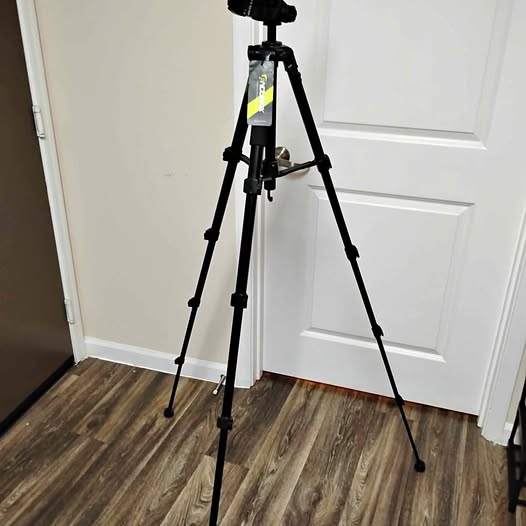 Black camera tripod stand with three adjustable legs and center column