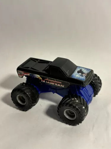 Diecast monster truck with blue and black body, oversized treaded wheels