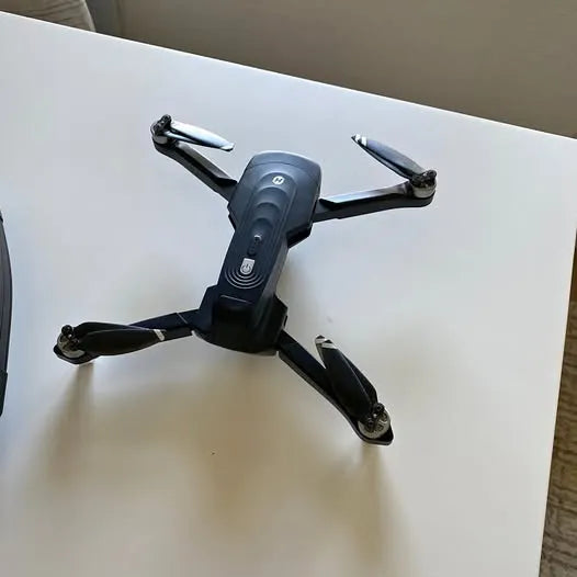 Quadcopter drone with four propeller arms, dark gray body and black blades