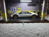 Diecast sports car model in display case, white with dark accents and rear wing