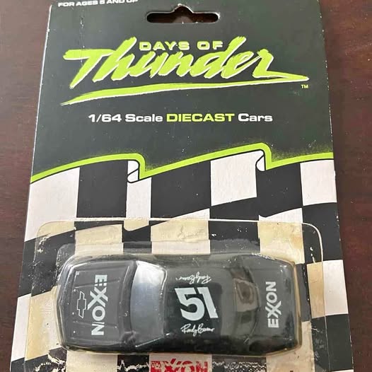 Black 1/64 scale diecast race car with decals on blister packaging