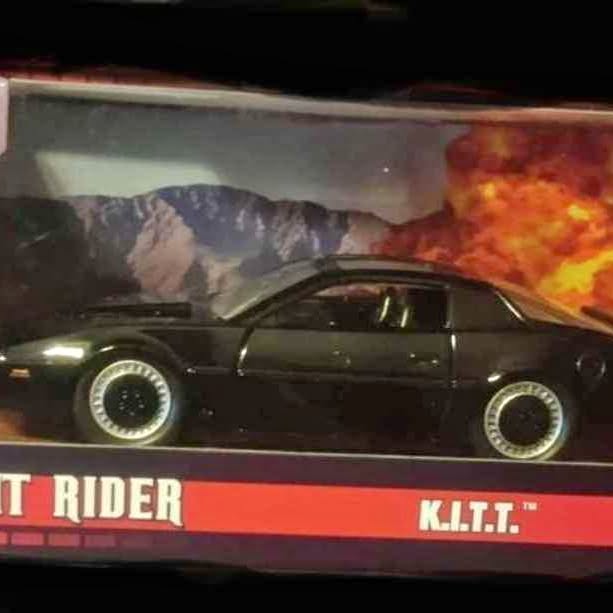 Black diecast K.I.T.T. style car with circular headlights and gold trim, side view.