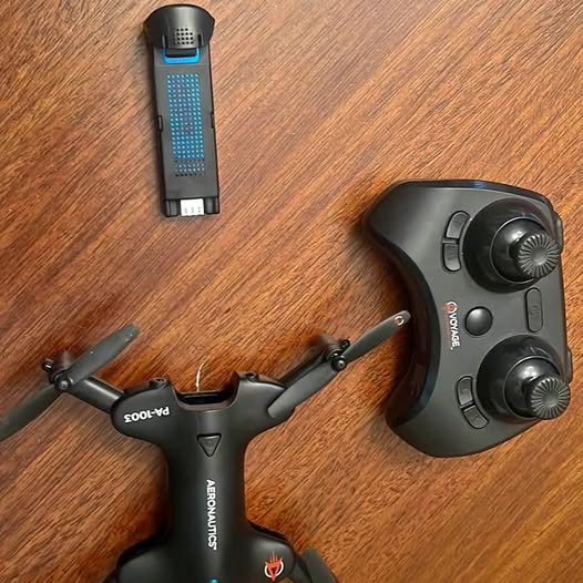 Foldable quadcopter drone and wireless controller on wood surface