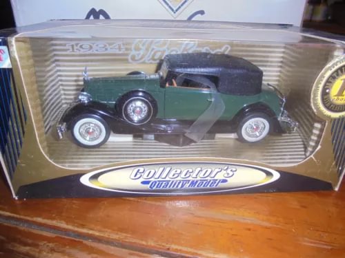 Dark green vintage diecast car in clear display box with ribbon-style logo