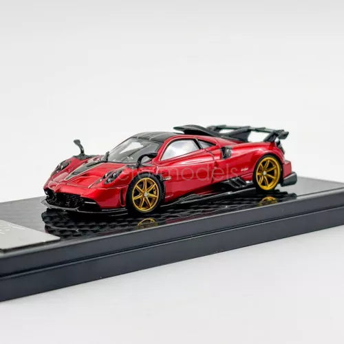 Red diecast sports car model on black display base, gold wheels