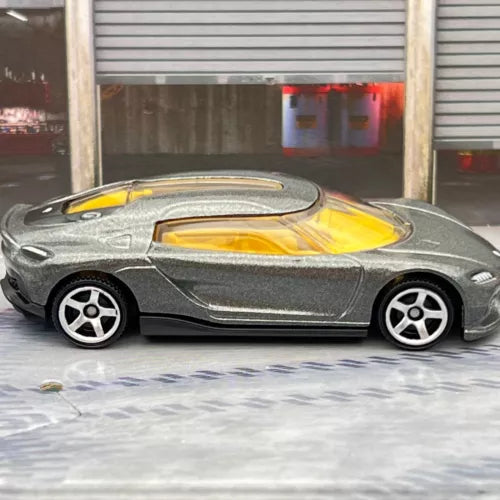 Grey diecast model car with yellow interior, side profile, white-spoke wheels