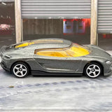 Grey diecast model car with yellow interior, side profile, white-spoke wheels