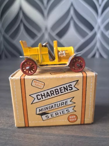 Miniature diecast toy car with yellow body and red wheels in Charbens box