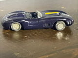 Diecast roadster convertible toy car, dark blue with yellow stripe, side view