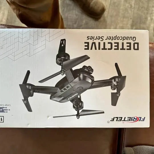 Folding quadcopter drone in retail box, four propellers, black and gray