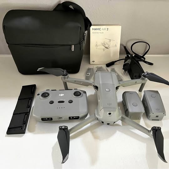 Drone kit with white quadcopter, dark controller, batteries, and instruction booklet.