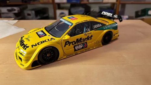 Yellow diecast 1:18 racing car model with black wheels and rear wing