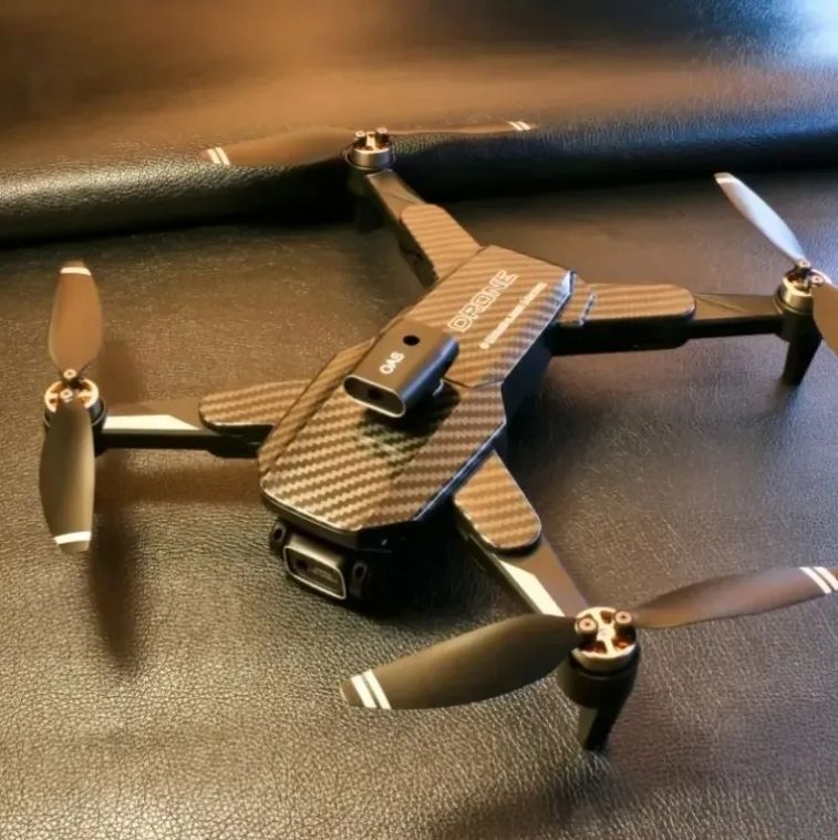 Camera drone with foldable arms, front camera module and four propellers, dark body.